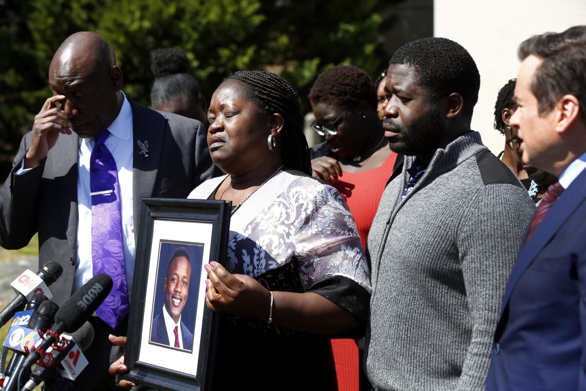 Caroline Ouko, mother of Irvo Otieno, holds a portrait of her son with attorney Ben Crump, left, her older son, Leon Ochieng and attorney Mark Krudys at the Dinwiddie Courthouse in Dinwiddie, Va., on Thursday, March 16, 2023. There is goodness in his music and that's all I'm left with now he's gone, Otieno's mother, Caroline Ouko, said at the news conference while clutching a framed photo of her son. (Daniel Sangjib Min/Richmond Times-Dispatch via AP)