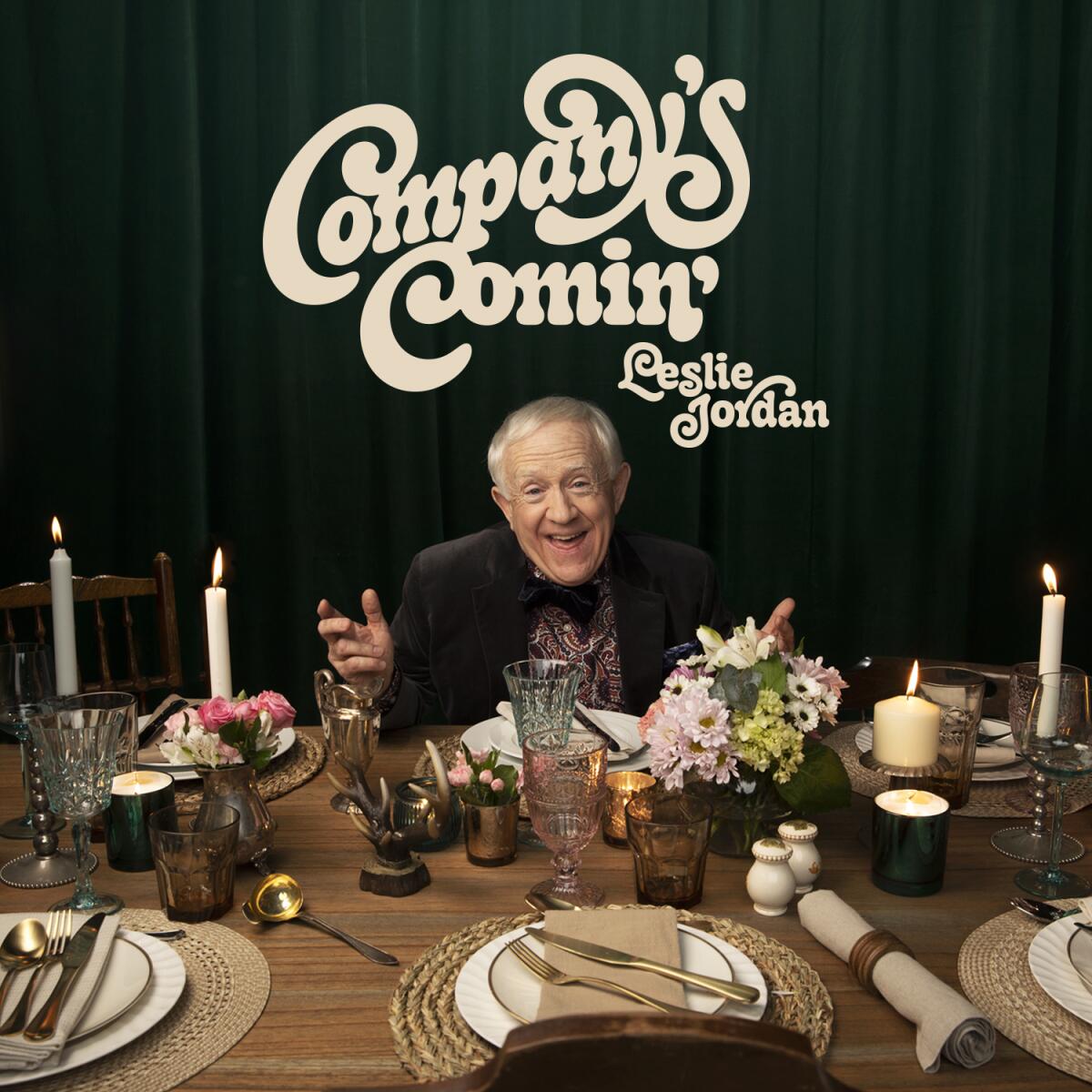 Leslie Jordan sits at a table with place settings and lit candles for the cover of his new album
