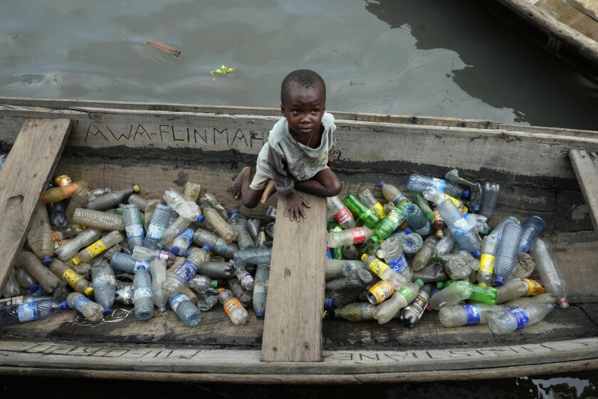 FILE - A child sits inside a canoe with empty plastic bottles he collected to sell for recycling in the floating slum of Makoko in Lagos, Nigeria, Nov. 8, 2022. Negotiators from around the world gather at UNESCO in Paris on Monday, May 29, 2023, for a second round of talks aiming toward a global treaty on fighting plastic pollution in 2024. (AP Photo/Sunday Alamba, File)