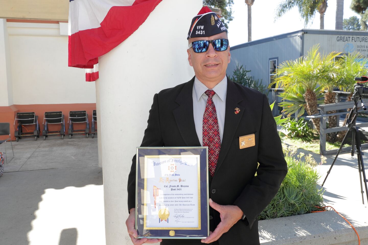 VFW Post Commander Julian Gonzales holds a plaque from the VFW that recognizes Post 5431 as an All-American Post