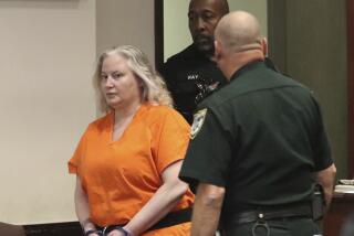 A pair of deputies walk Tammy Sytch dressed in an orange jail jumpsuit and handcuffs inside a courtroom