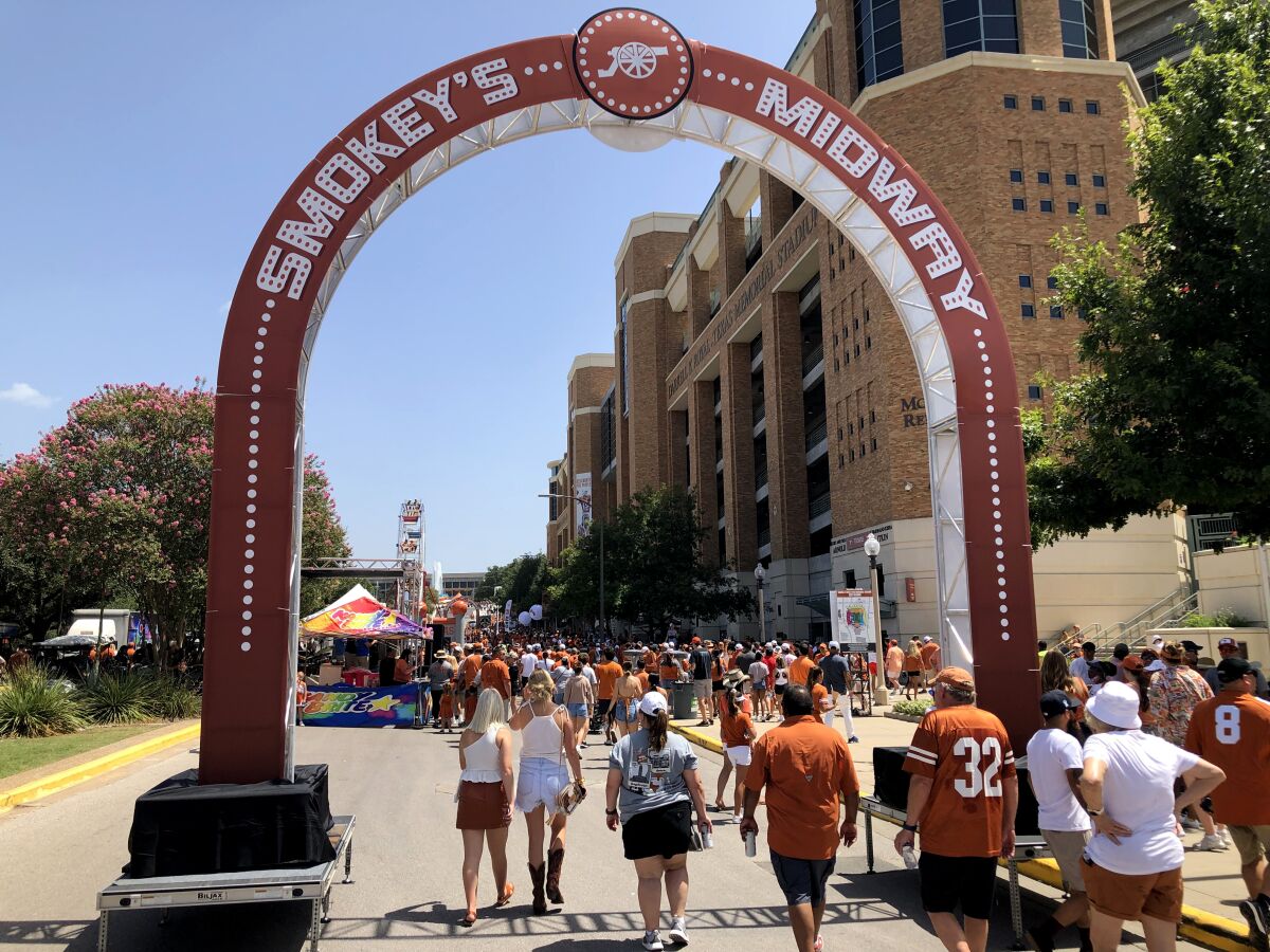 Texas Longhorns fans walk under an arch on a street