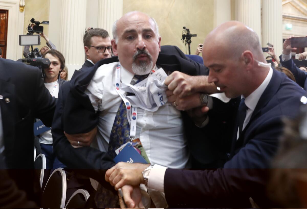 Security staff grapple with a man before a news conference by President Trump and Russian President Vladimir Putin.
