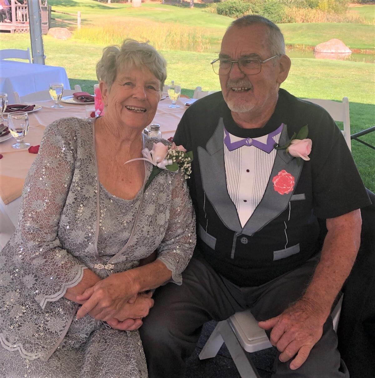 A woman wears a lacy gray dress and a man a T-shirt imprinted with a fake tuxedo front. 