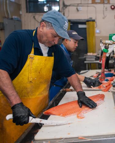 Employees work in the back room at Fish King, preparing salmon and cleaning seafood.