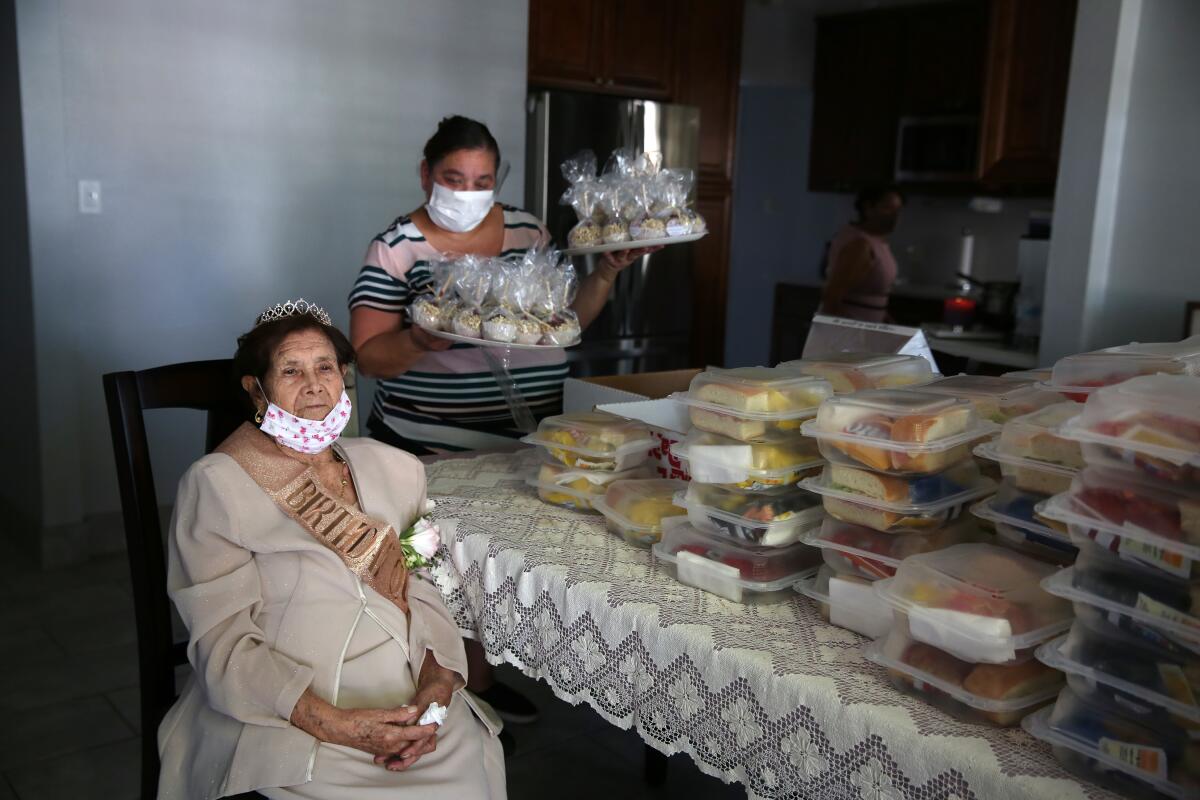 Angelita Arellano waits for the start of her 98th birthday party as Angelica Gurrola sets out food for guests