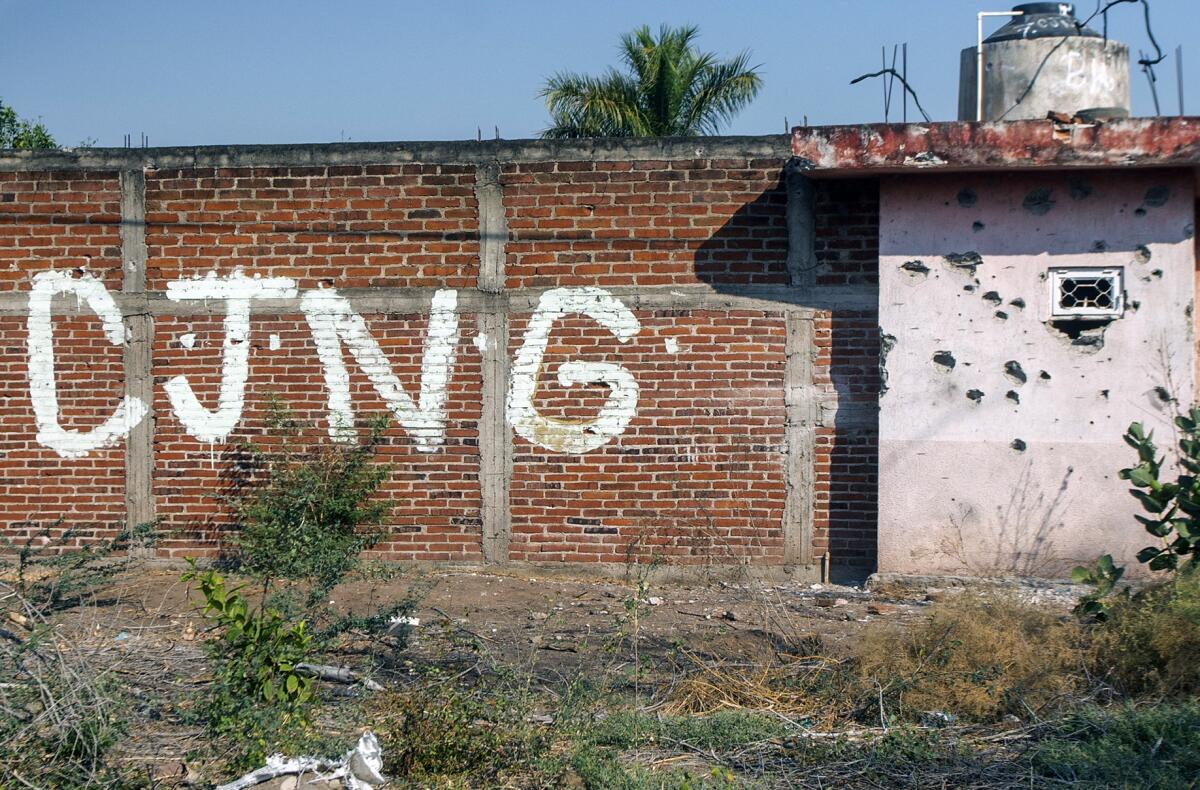 View of a bullet-riddled wall bearing the initials of Cartel Jalisco Nueva Generacion (CJNG) in Aguililla