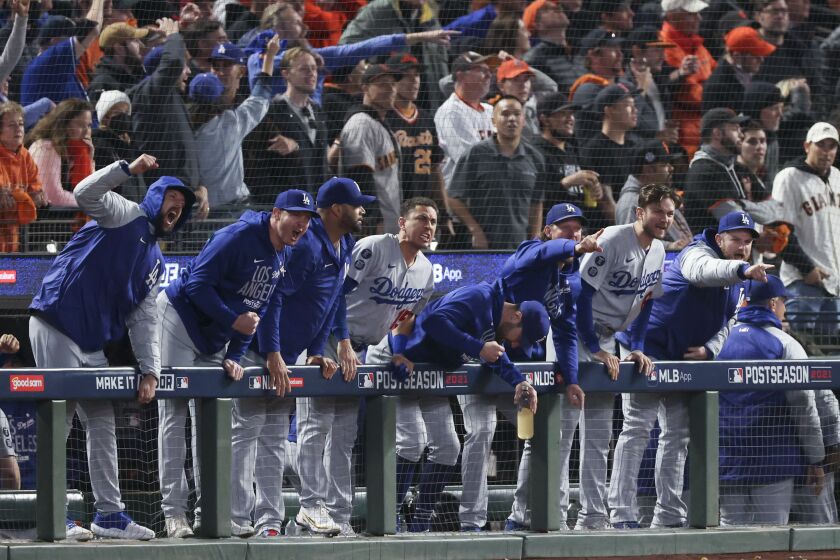 San Francisco, CA - October 14: The Los Angeles Dodgers dugout cheers after an RBI single by Cody Bellinger during the ninth inning in game five of the 2021 National League Division Series against the San Francisco Giants at Oracle Park on Thursday, Oct. 14, 2021 in San Francisco, CA. (Robert Gauthier / Los Angeles Times)
