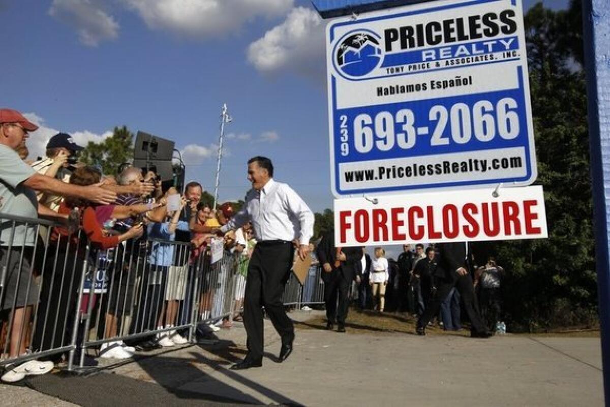 Mitt Romney greets the crowd as he arrives for a campaign rally in front of a foreclosed home in Lehigh Acres, Fla.