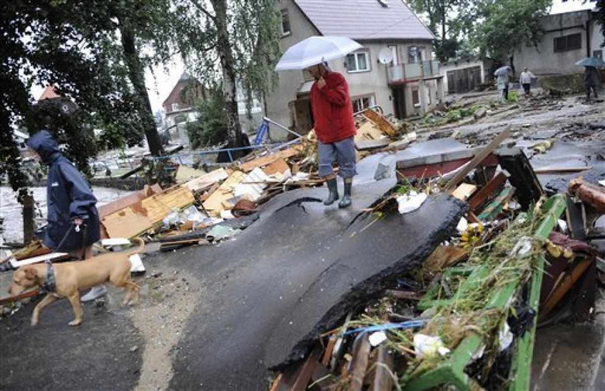 Residents walk among the debris following flooding in Bogatynia, Poland, on Saturday Aug. 7, 2010. The floods struck late Friday but worsened on Saturday, leaving three-fourths of the southwestern Polish town of Bogatynia inundated after the Miedzianka River spilled its banks. (AP Photo/Robert Steiner )