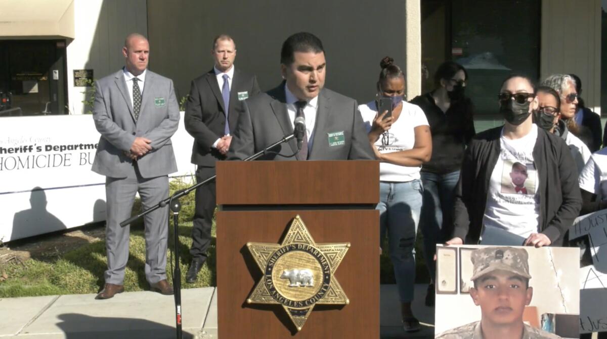 People stand behind a lectern with the L.A. County Sheriff's Department logo on it