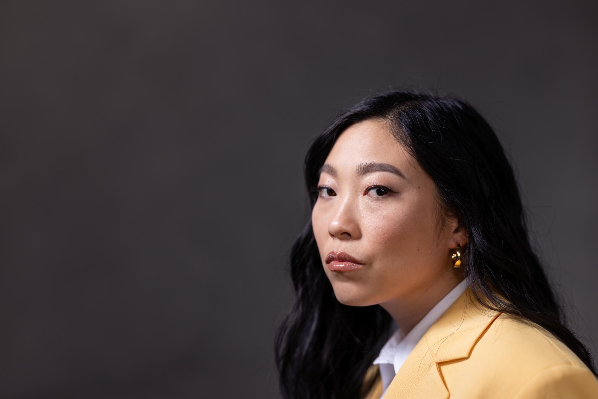 Nora Lum (Awkwafina) looks serious posing for a portrait.