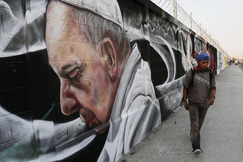A man walks past a mural painted in honor of Pope Francis' visit in Ecatepec, Mexico.