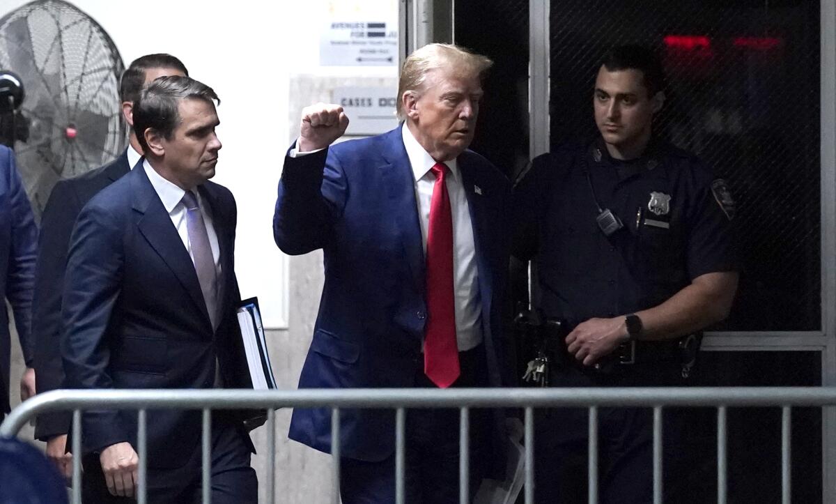 Former President Trump raises his fist as he walks toward court 