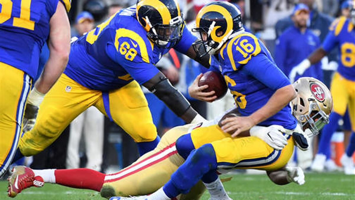 Rams quarterback Jared Goff, wearing the team's throwback uniform, is sacked by 49ers defensive lineman Ronald Blair.