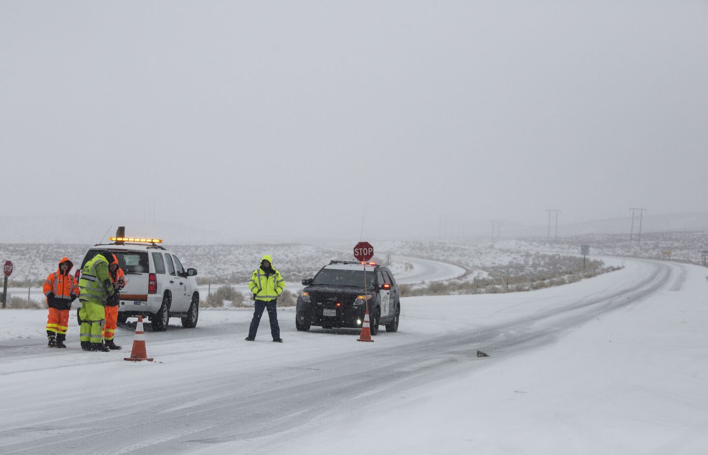 A CHP officer maintains a checkpoint to ensure vehicles are compliant with R2 chain restrictions on the northbound 395 just north of Bishop as snow falls on the Eastern Sierra Nevada.