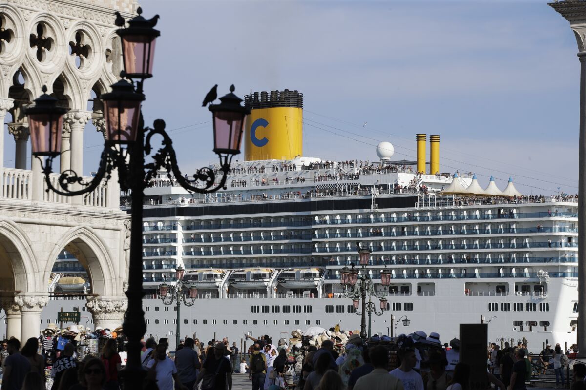 FILE-- A cruise ship passes by St. Mark's Square filled with tourists, in Venice, Italy, Sunday, June 2, 2019. Declaring Venice's waterways a “national monument,” Italy is banning mammoth cruise liners from sailing into the lagoon city, which risked within days being declared an imperiled world heritage site by the United Nations. Culture Minister Dario Franceschini said the ban will take effect on Aug. 1 and was urgently adopted at a Cabinet meeting on Tuesday. . (AP Photo/Luca Bruno)
