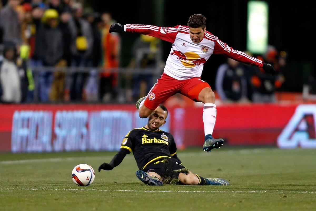 New York Red Bulls' Sal Zizzo jumps over Justin Meram of the Columbus Crew SC while chasing after the ball.