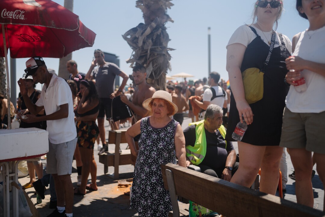 Une femme assistant à la parade de la fierté s'arrête pour regarder les gens danser.