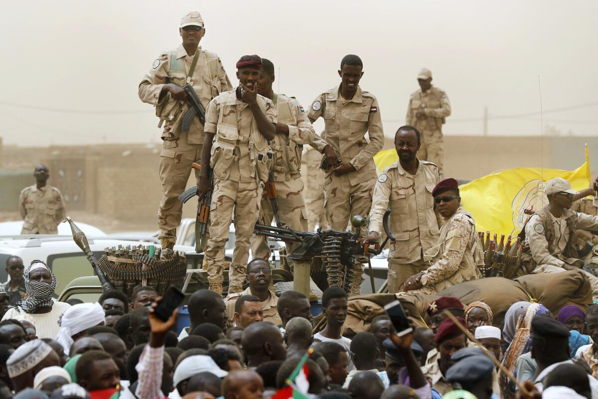 Sudanese soldiers from the Rapid Support Forces unit stand on their vehicle