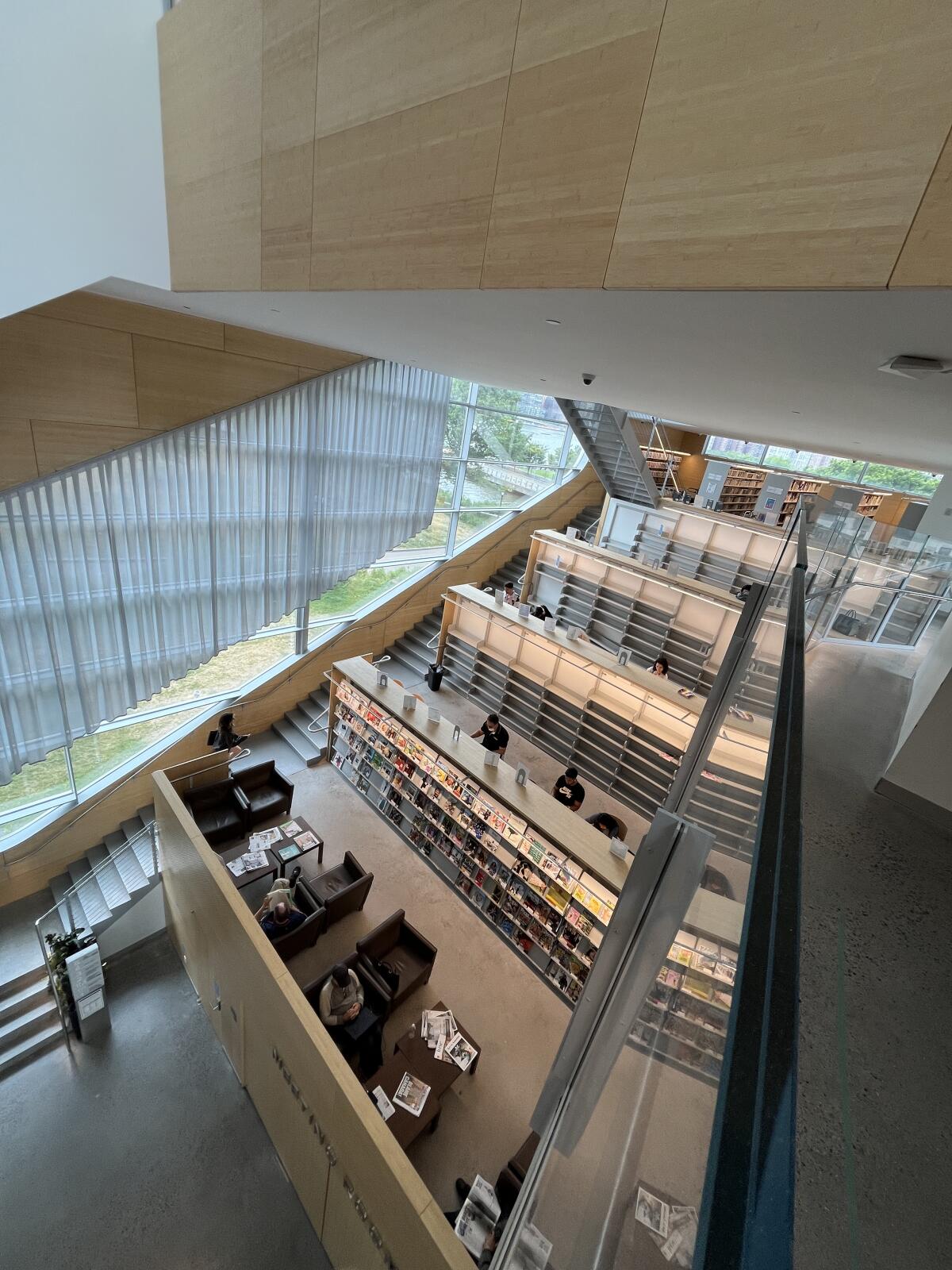 A view from overhead shows a series of stepped mezzanines lined with bookshelfs — some empty.