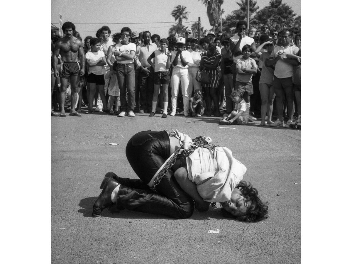 July 1984: Escape artist Tim Eric tries to break free from chains and a straitjacket as a crowd watches in Venice Beach.