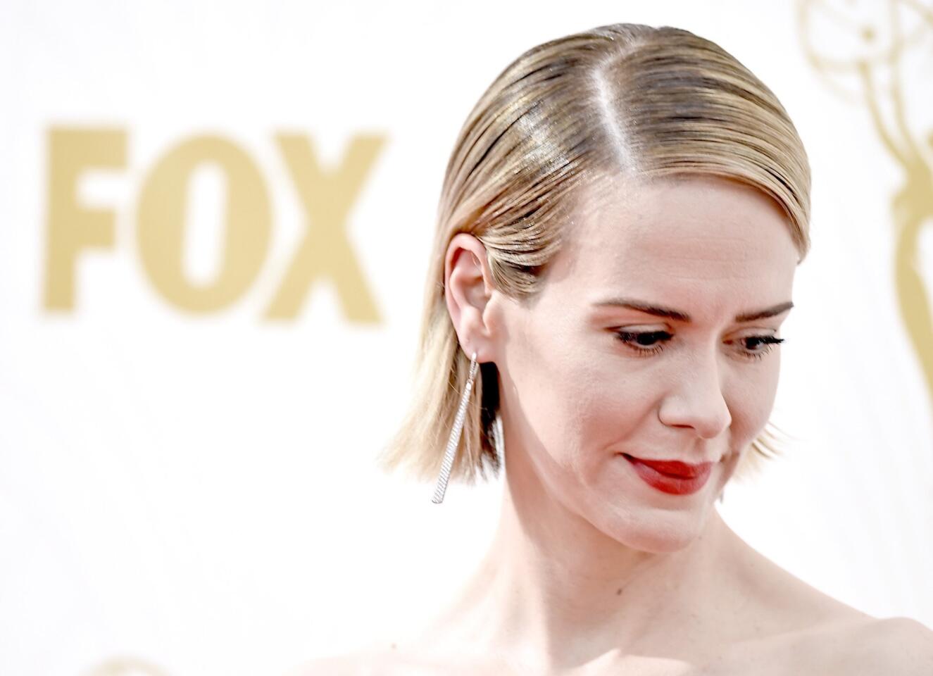 Sarah Paulson's slicked-back hair features a deep side part.