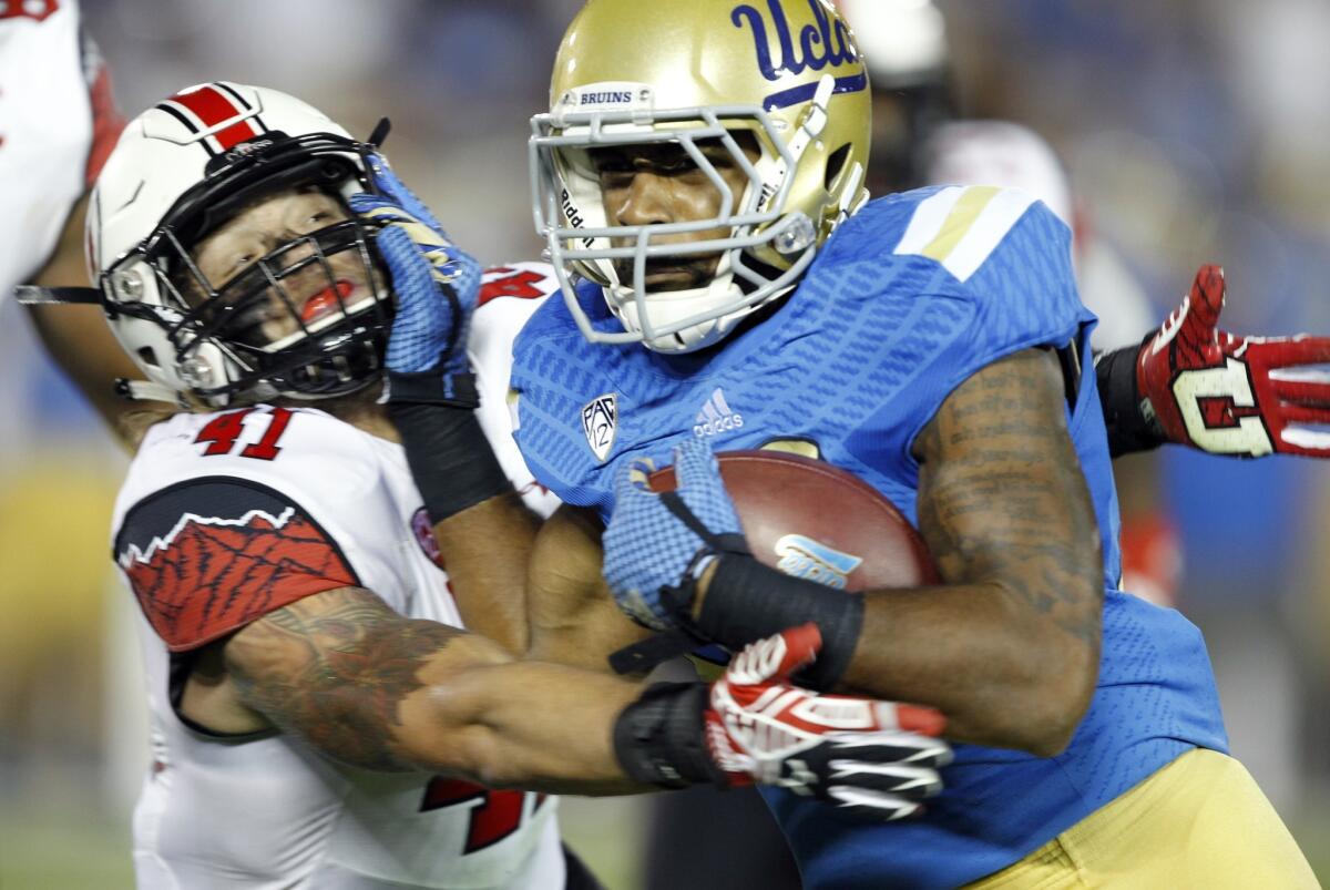 UCLA running back Nate Starks tries to fend off Utah linebacker Jared Norris during the second half of the Bruins' 30-28 loss to the Utes on Oct. 4.