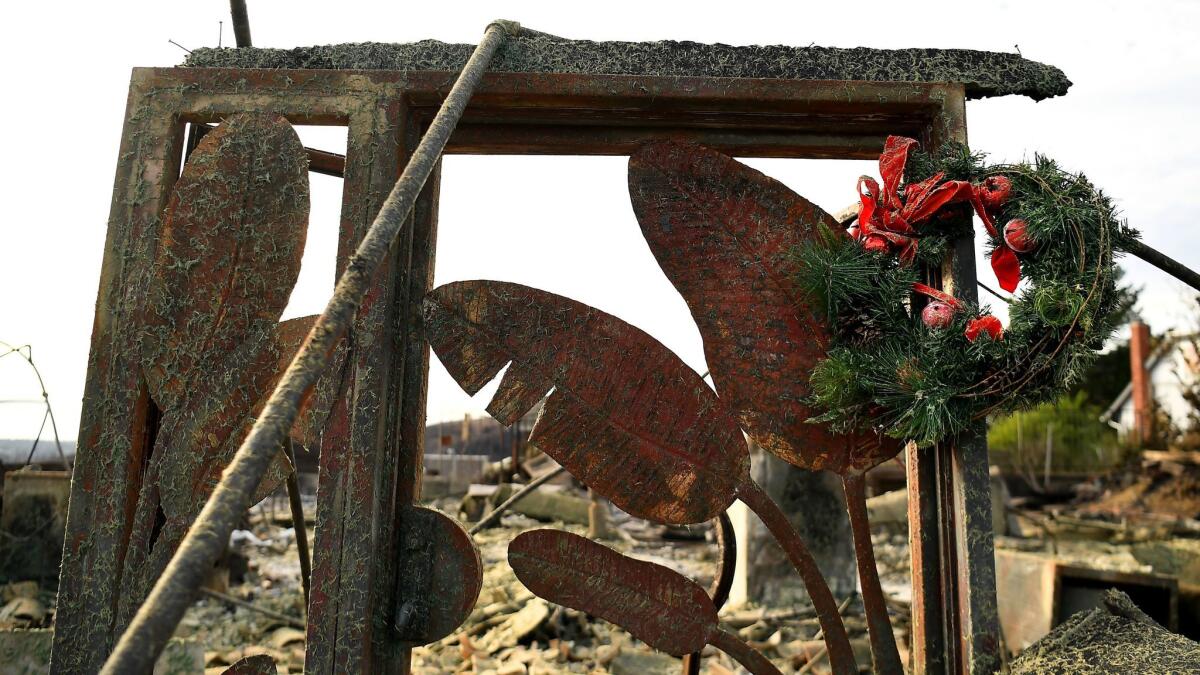 A Christmas wreath hangs from a doorway of a burned house along Alverstone Ave. in Ventura on Christmas Eve.