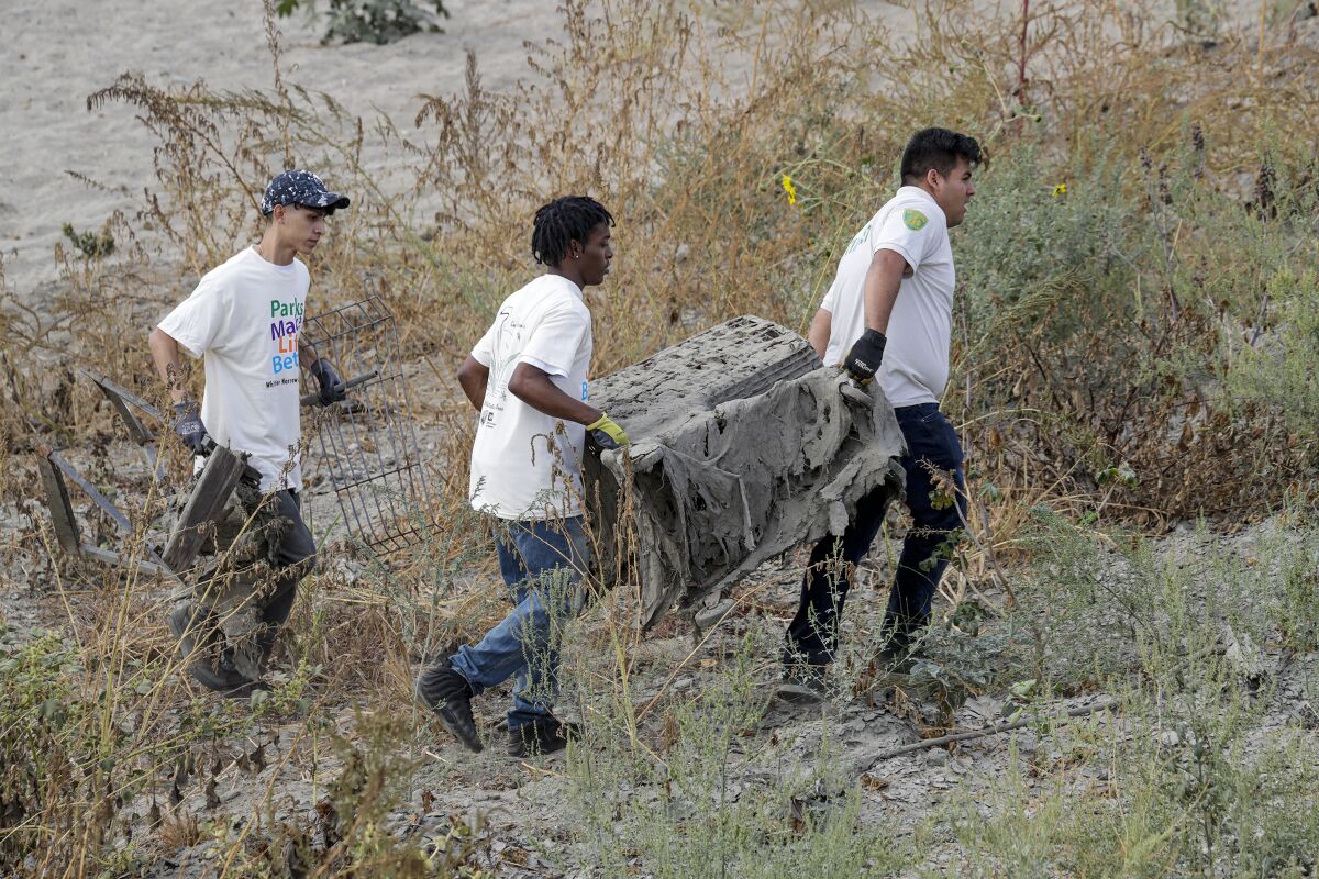 Jesse Murillo, 18, left, Donnell Dorsey, 20, and Juan Guillen, 22, all from Whittier Narrows Nature Center, help to clean up Whittier Narrows Park on Saturday as part of National Public Lands Day.