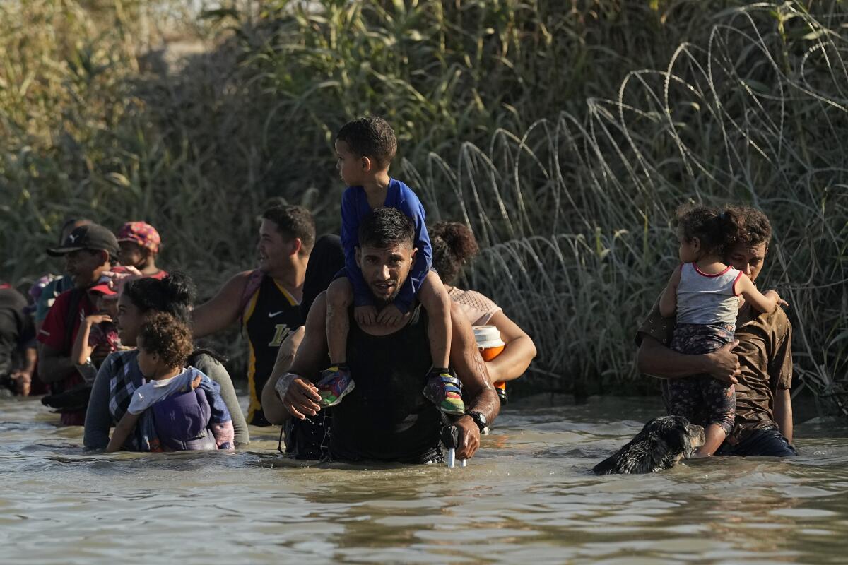 Migrants navigate along the banks of the Rio Grande after crossing from Mexico into the U.S.