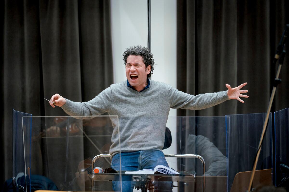 Dudamel conducts from behind plexiglass.