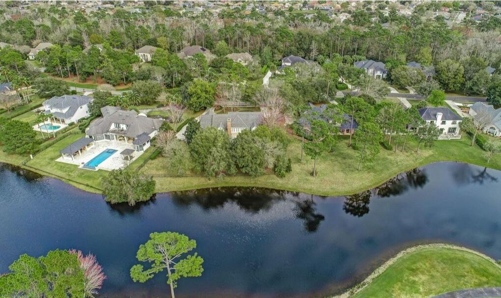 The brick-clad two-story features a motor court in front and a dining gazebo out back that descends to a pond.