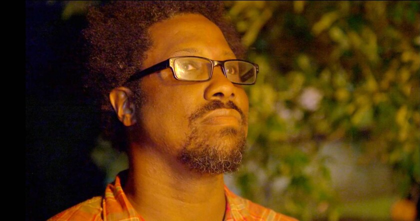 A burning cross, ignited by members of the Ku Klux Klan, is reflected in the spectacles of W. Kamau Bell, host of the new CNN series "United Shades of America."