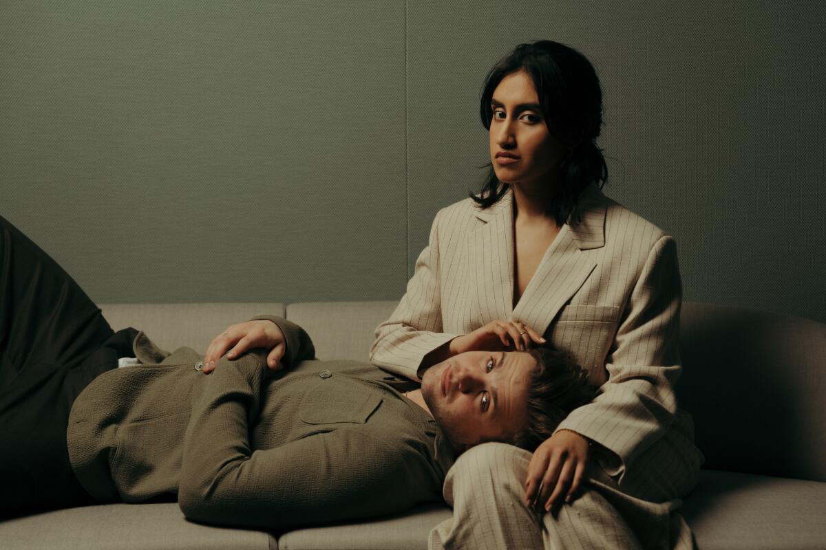 Two actors on a couch, one lying with his head in the other's lap