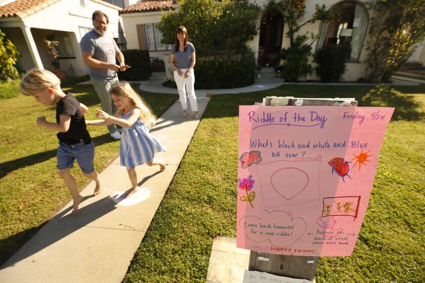 LOS ANGELES, CA - APRIL 24: Jay and Kate Larsen with their two children Reid, 6, and River, 4, started posting a hand-painted riddle on the front lawn each day to brighten up the lives of Mar Vista neighbors after the coronavirus lockdown started. It has become a phenom in the neighborhood, with others using their front yards for riddles, games, and whimsical displays. The Larsons then helped organize a treasure hunt for kids and families creating closer neighborhood bonds, even at a safe distance. Mar VIsta on Friday, April 24, 2020 in Los Angeles, CA. (Al Seib / Los Angeles Times)