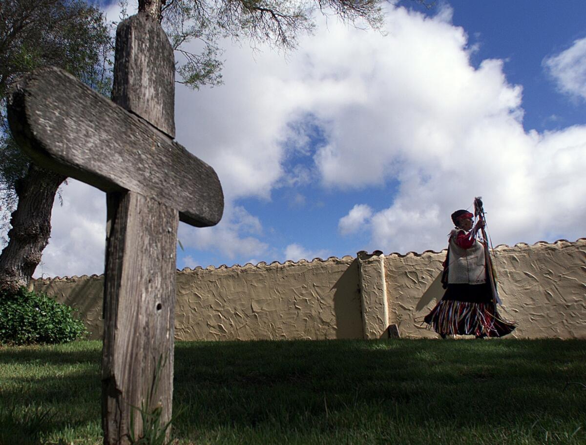 Adelina Alva Padilla, spiritual leader of the Santa Ynez Chumash, walks past a grave marker at Mission Santa Ines.