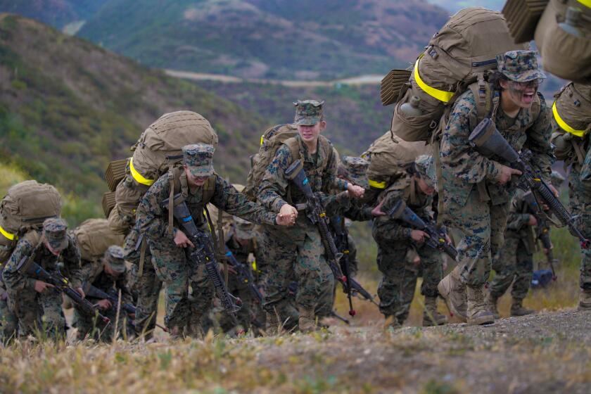 Camp Pendleton, CA - April 22: On Thursday, April 22, 2021 at Camp Pendleton, CA., three women reach hold hands as they crest over the final ridge of the reaper during the crucible. Immediately after in a brief ceremony, the recruits are awarded their eagle, globe and anchor from their drill instructor and have earned the title U.S. Marine. (Nelvin C. Cepeda / The San Diego Union-Tribune)