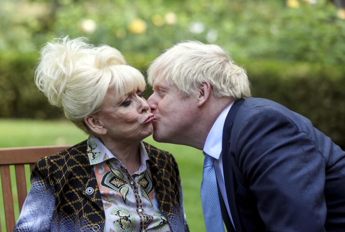 FILE - In this Sept. 2, 2019 file photo, British actress Barbra Windsor is kissed by British Prime Minister Boris Johnson, in 10 Downing Street, London, Monday, Sept. 2, 2019, to promote Dementia Care. Windsor, whose seven-decade career ranged from cheeky film comedies to the soap opera “EastEnders” has died at the age of 83 at a care home in London, husband Scott Mitchell said Thursday, Dec. 10, 2020. (Simon Dawson/Pool via AP, pool, file)