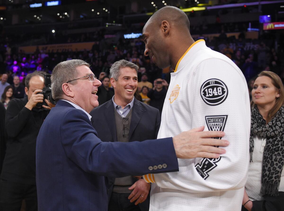 International Olympic Committee President Thomas Bach, left, talks to Kobe Bryant prior to the Lakers' game against Charlotte on Sunday at Staples Center.