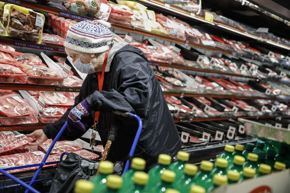 FILE - An elderly shopper wears personal protective equipment as she browses the meat section of a grocery store on April 18, 2020, in the Harlem neighborhood of the Manhattan borough of New York. As war, climate change and inequality have consumed much of the 2022 U.N. General Assembly, leaders have largely left unsaid the historic growth of the planet’s aging population. (AP Photo/John Minchillo, File)