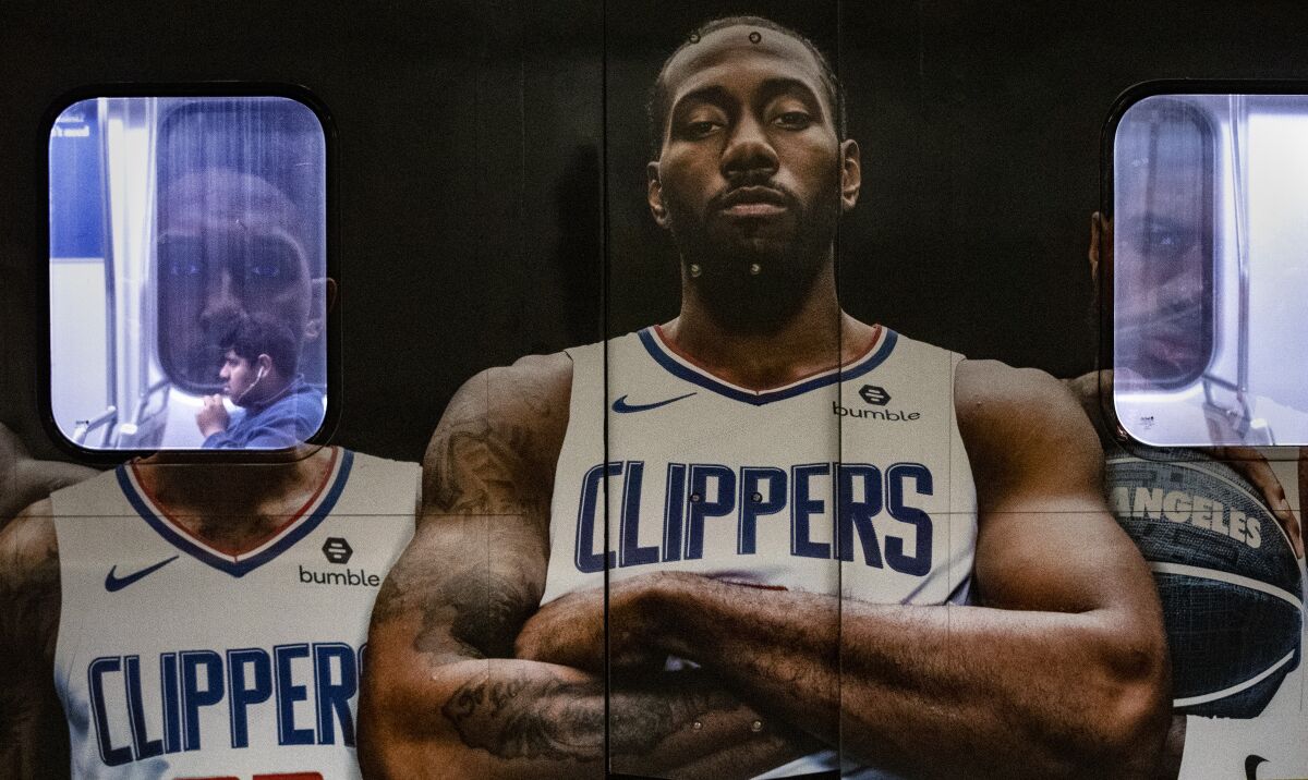 A man waits on a Metro A Line train wrapped with images of Clippers players at the 7th Street/Metro Center subway station in Los Angeles.