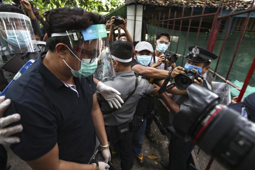 Canadian pastor David Lah, covered with face shield and mask, is escorted by police upon arrival at a township court for his first court appearance Wednesday, May 20, 2020, in Yangon, Myanmar. Pastor Lah attended a court hearing related to charges filed against him for allegedly organizing public Christian activities in Yangon back in April, after the regional government banned mass gatherings in mid-March to curb the spread of the coronavirus.(AP Photo/Thein Zaw)