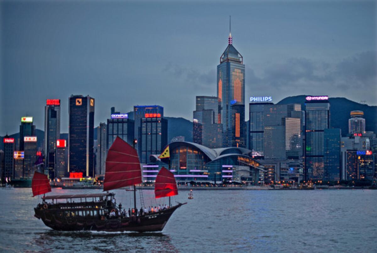 A junk sails on Victoria Harbor in front of the Hong Kong skyline.