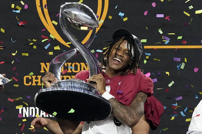 Alabama's Jameson Williams (1) holds up the winner's trophy as coach Nick Saban.