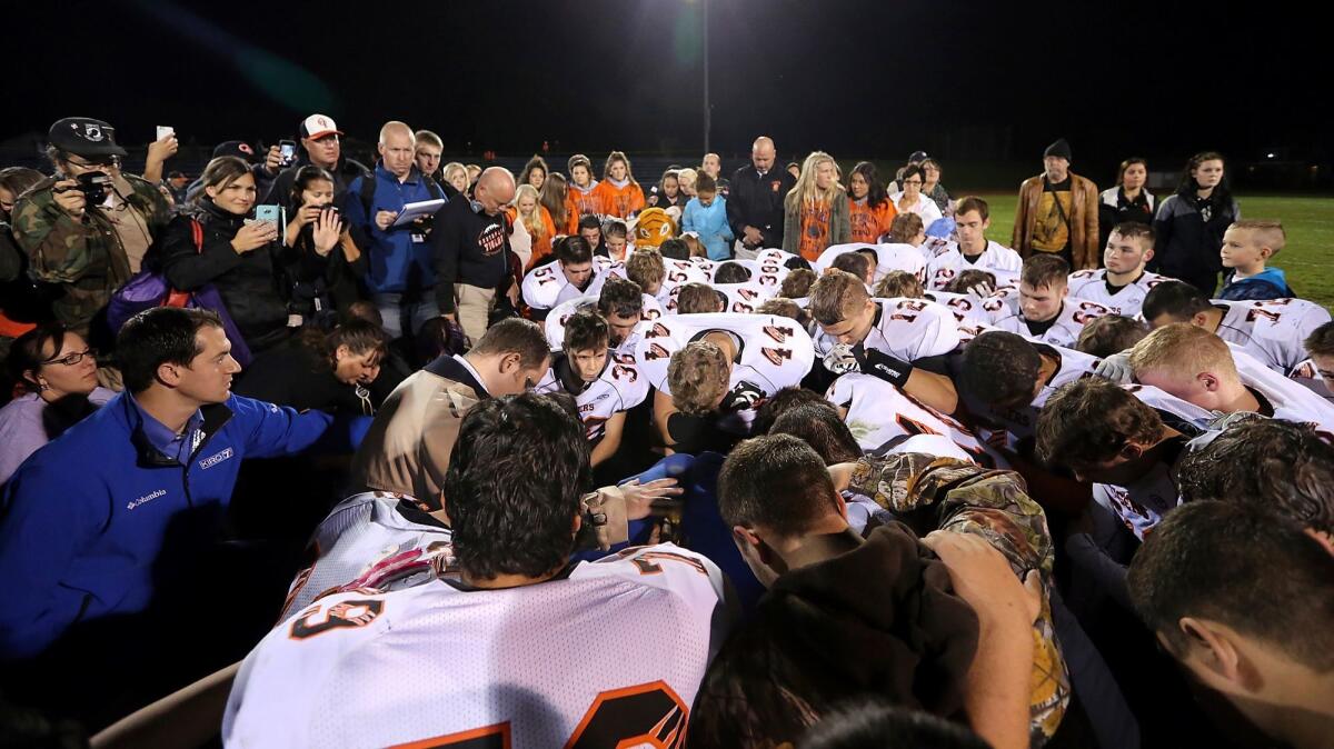 Players gather around Bremerton, Wash., High School assistant football coach Joe Kennedy, obscured in center, for prayer after a game in 2015.