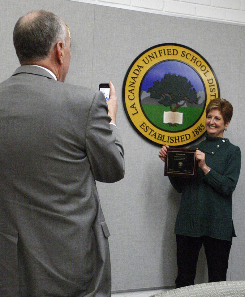 Outgoing school board member Susan Boyd holds a plaque in front of a LCUSD emblem for a photo being taken by her husband Jim at a La Canada Unified School District Office school board meeting on Tuesday, December 10, 2013. Three outgoing members, including Scott Tracy, Susan Boyd, and Joel Peterson, ended their terms on the school board, and three new members, including Kaitzer Puglia, David Sagal, and Dan Jefferies were sworn in. (Tim Berger/Staff Photographer)