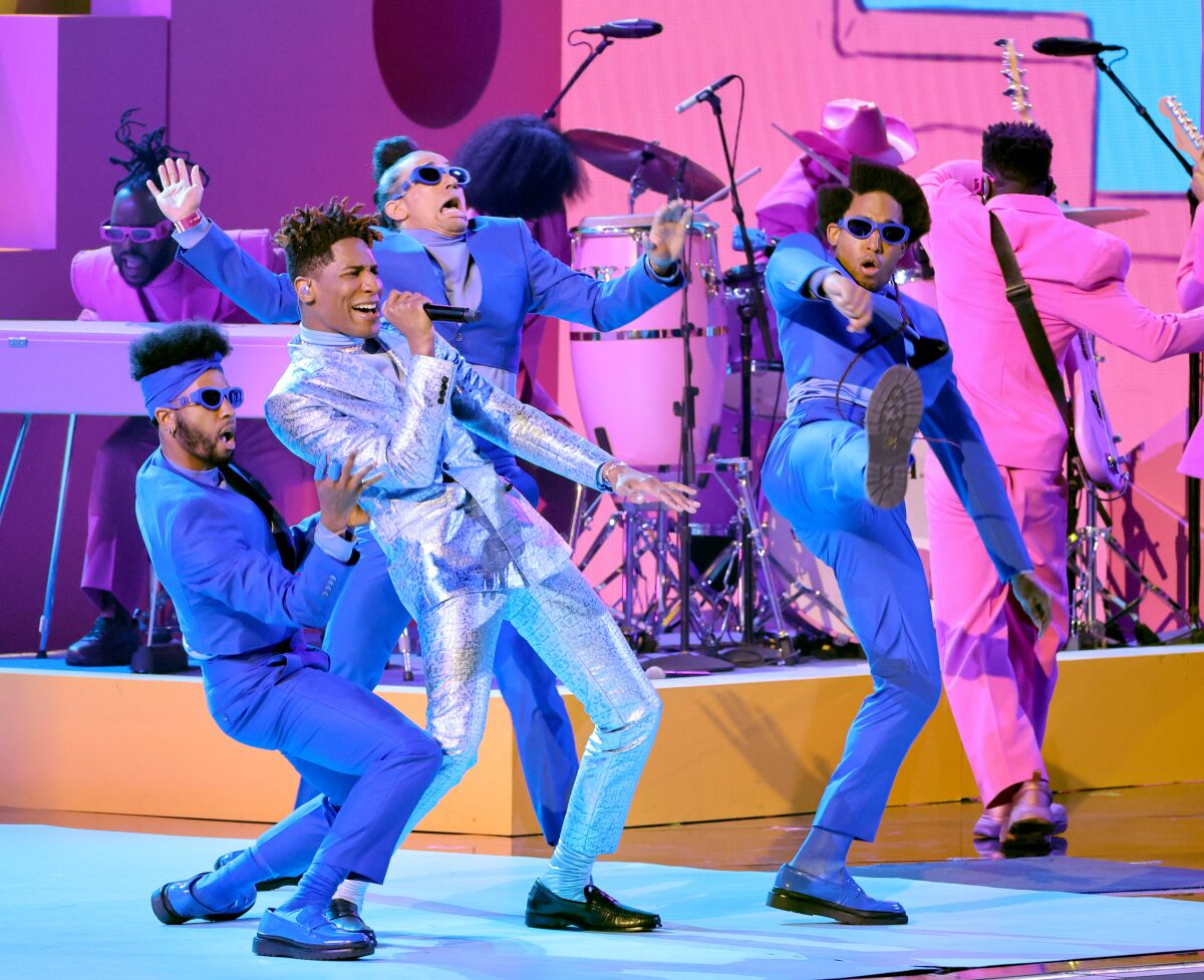 Men in bright-colored suits singing and dancing onstage.