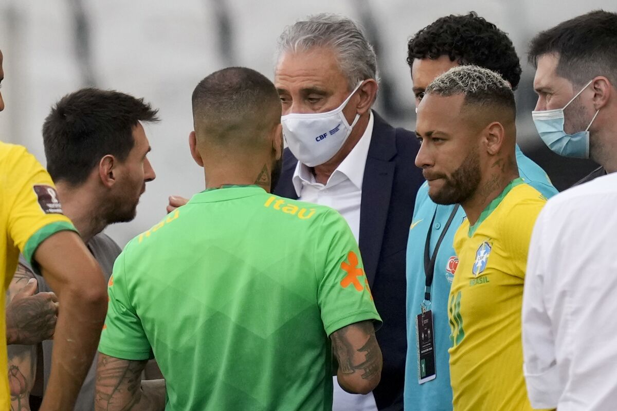 Argentina's Lionel Messi, left, talks to Brazil's coach Tite and Brazil's striker Neymar, right, after the qualifying soccer match for the FIFA World Cup Qatar 2022 was interrupted by health officials at Neo Quimica Arena stadium in Sao Paulo, Brazil, Sunday, Sept.5, 2021. Argentina walked off the field shortly after the start of the South American classic when health officials came onto the pitch following coronavirus concerns about some Argentina players.(AP Photo/Andre Penner)