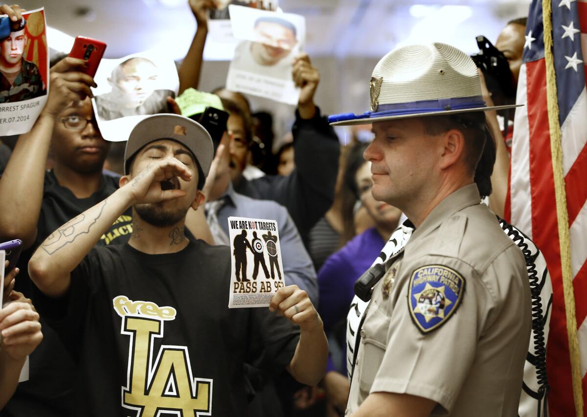 A California Highway Patrol officer stands outside the office of Gov. Brown last month as protesters shouting "black lives matter" demand passage of racial profiling legislation.